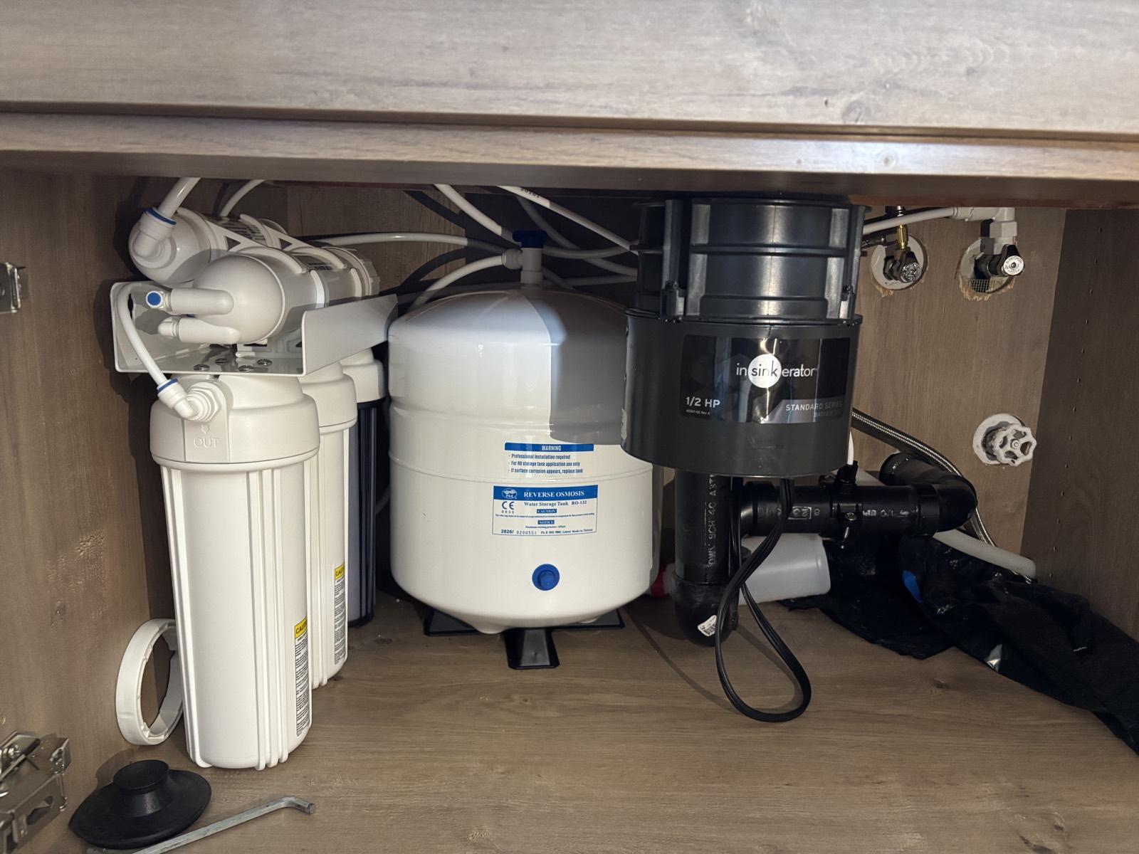 Whole-home water softener and brine tank installed in a garage, control valve display showing the system running a backwash cycle