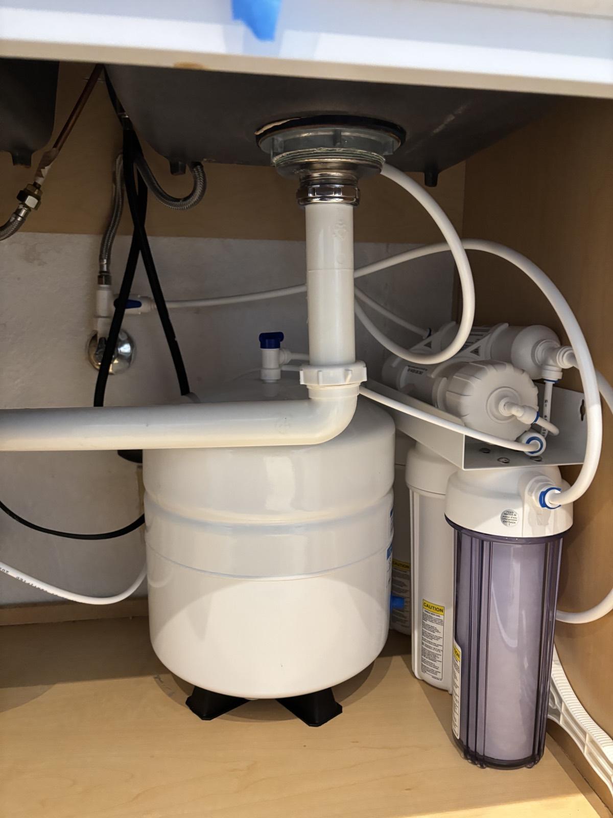 Under-sink reverse osmosis system with pre-pressurized storage tank and filter housings neatly installed in a kitchen cabinet